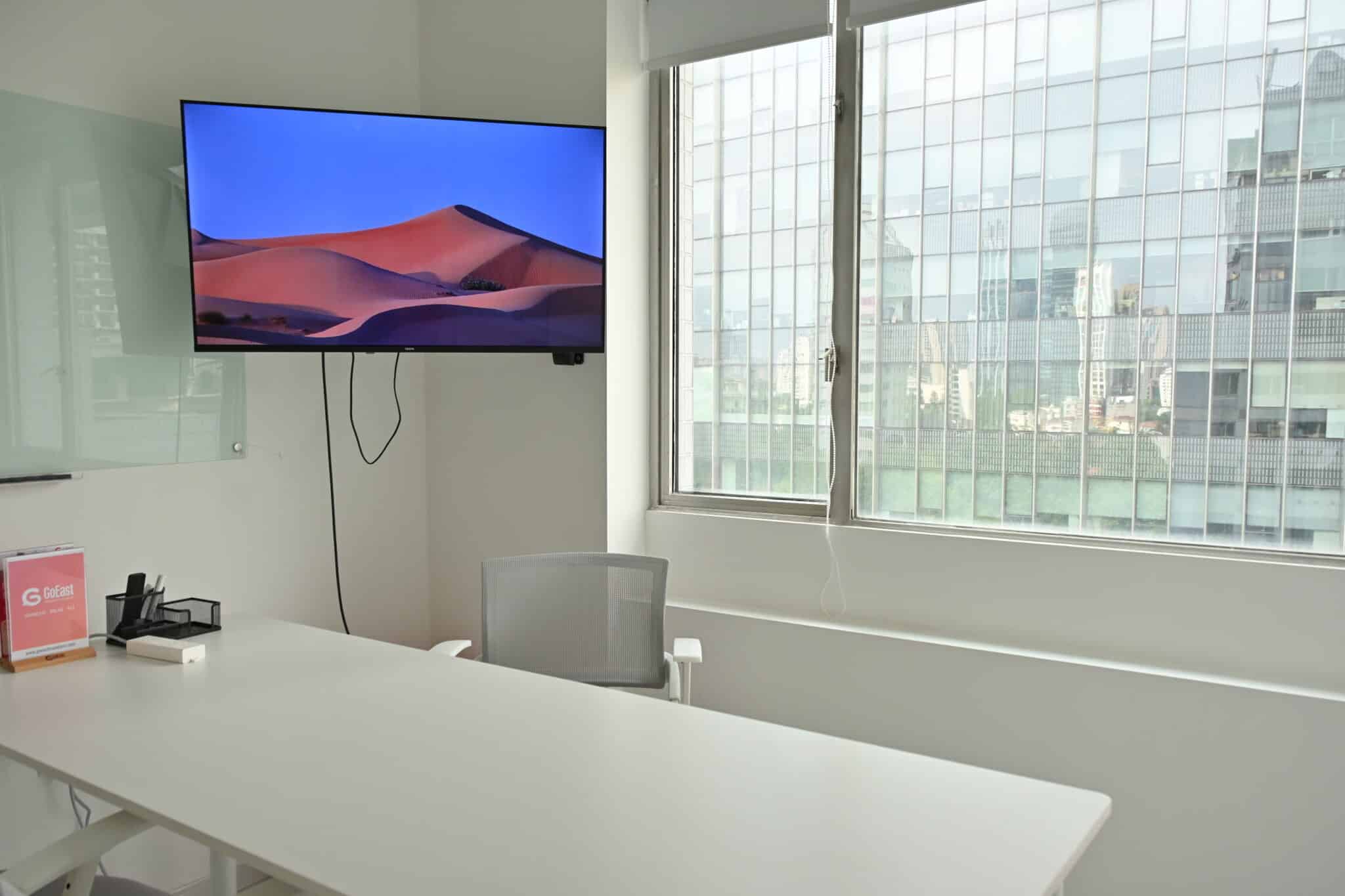 A classroom with a wall-mounted screen and large windows at GoEast Changning